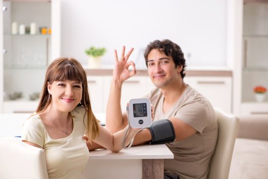Wife checking husband's blood pressure  
