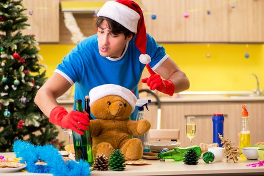 Young man cleaning kitchen after Christmas party 