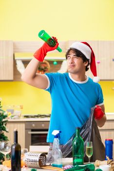 Young man cleaning kitchen after Christmas party 