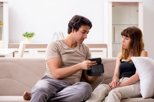 Husband checking wife's blood pressure