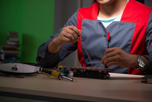 Young handsome repairman repairing computer 