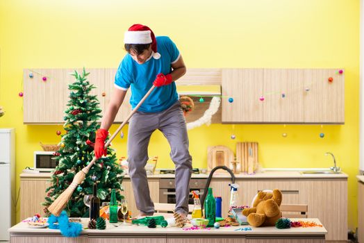 Young man cleaning kitchen after Christmas party 