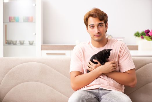 Young man playing with kitten at home