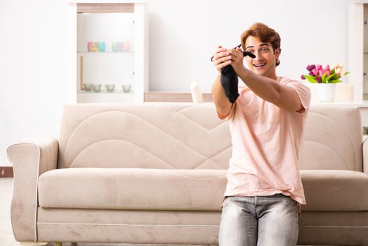 Young man playing with kitten at home