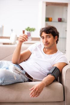 Young man measuring blood pressure at home