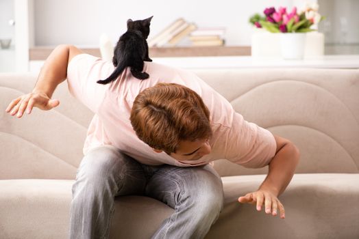 Young man playing with kitten at home