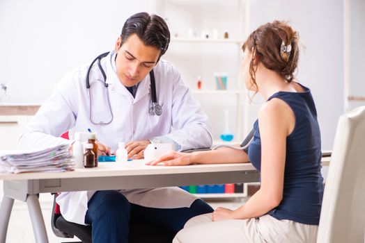Young doctor checking woman's blood pressure