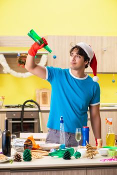 Young man cleaning kitchen after Christmas party 