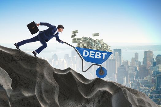 Businessman pushing wheelbarrow with dollars downhill