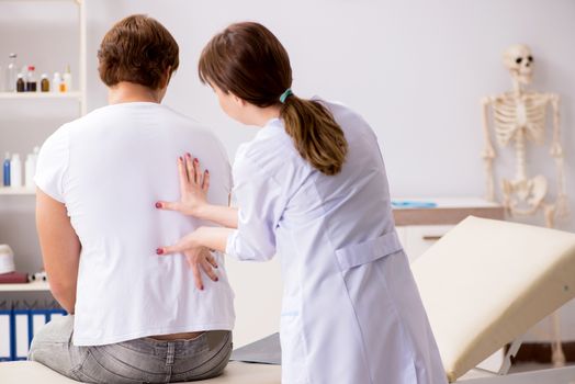 Male patient visiting young female doctor chiropractor 