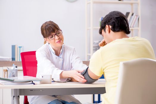 Young doctor checking patients blood pressure