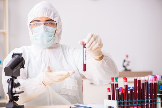 Young handsome lab assistant testing blood samples in hospital 