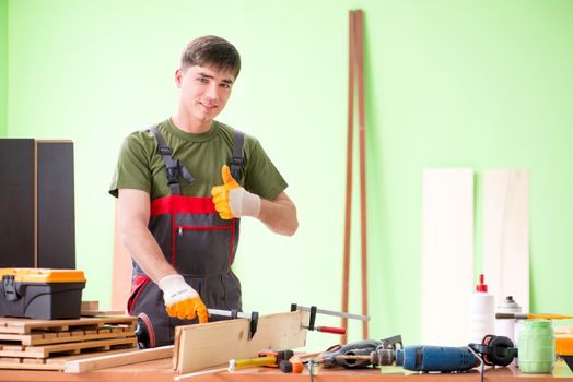 Young man carpenter working in workshop 