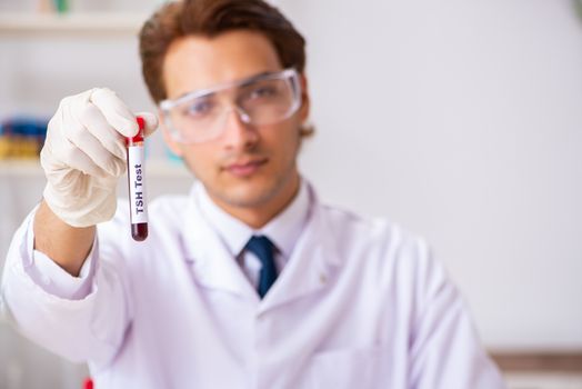 Young handsome lab assistant testing blood samples in hospital 