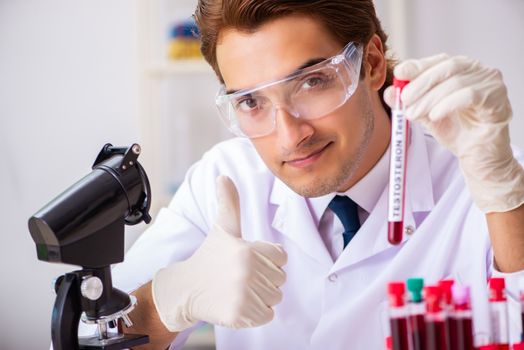 Young handsome lab assistant testing blood samples in hospital 