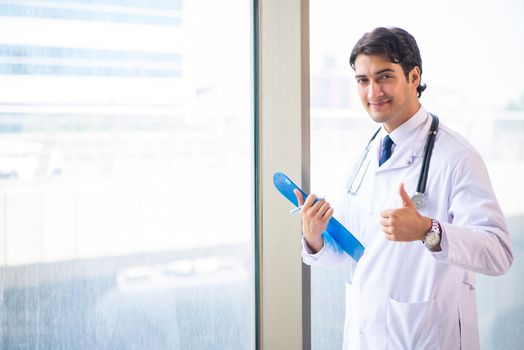 Young handsome doctor standing at the window 