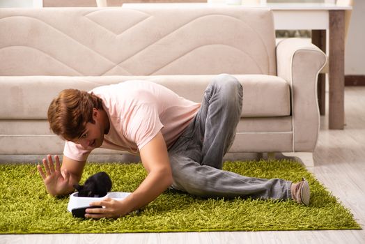 Young man playing with kitten at home