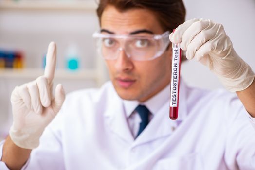 Young handsome lab assistant testing blood samples in hospital 