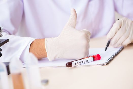 Young handsome lab assistant testing blood samples in hospital 