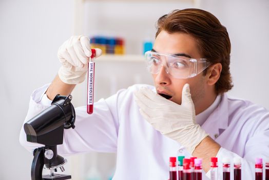 Young handsome lab assistant testing blood samples in hospital 