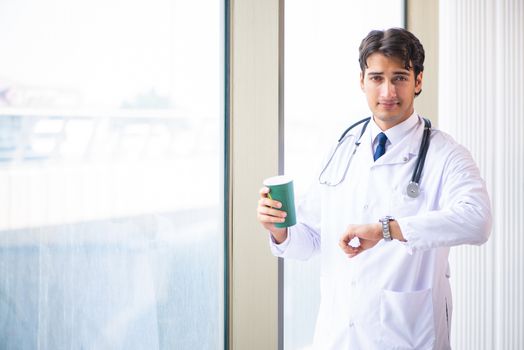 Young handsome doctor standing at the window 