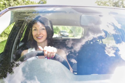 Beautiful adult happy woman driving her car in summer day