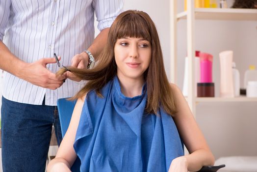 Young woman visiting young handsome barber 