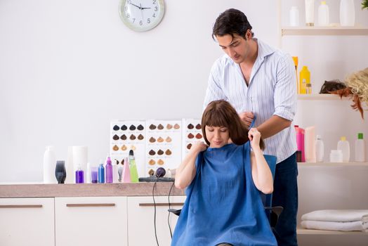 Young woman visiting young handsome barber 