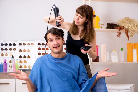 Young attracrive man visiting female barber 