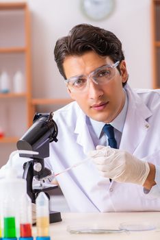 Young handsome biochemist working in the lab  