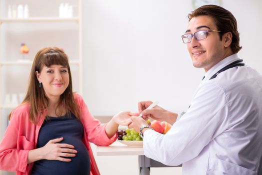 Pregnant woman visiting doctor discussing healthy diet