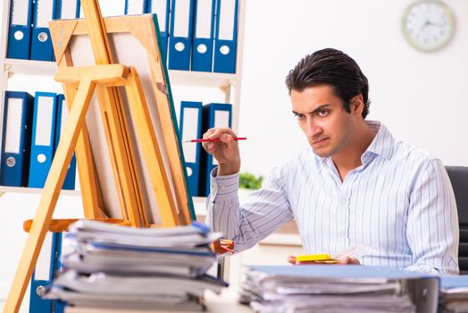 Young handsome employee enjoying painting at the office 