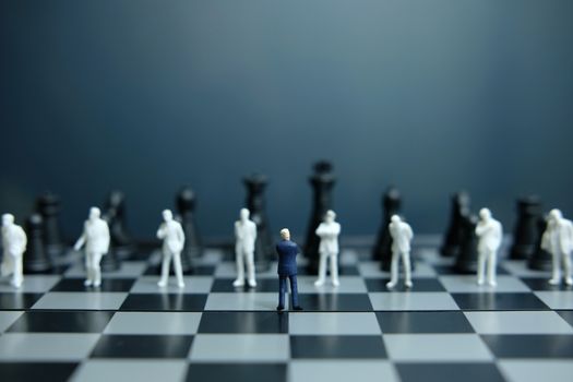 Business strategy conceptual photo - Miniature of businessman standing on chessboard