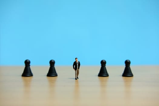 Business strategy conceptual photo - Miniature of businessman walking in the middle of pawn chess piece