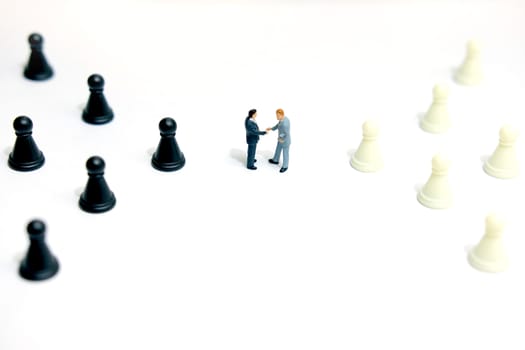Miniature business concept - two businessman make handshake agreement between chess pawn