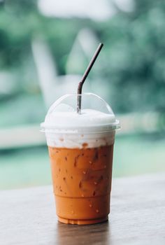 Closeup thai milk tea on wood table with nature background