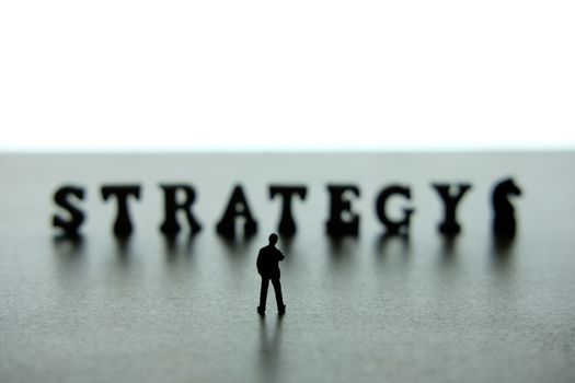 Silhouette of miniature businessmen standing and thinking in front of strategy word block puzzle. image photo