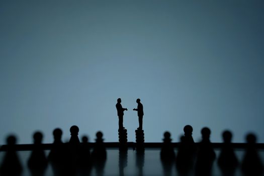 Business strategy conceptual photo - Silhouette of miniature of businessman make partnership agreement standing above castle pawn in the middle of chessboard