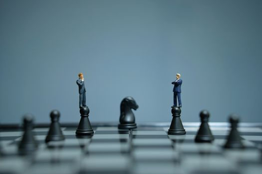 Business strategy conceptual photo - miniature businessman standing above castle pawn on a chessboard