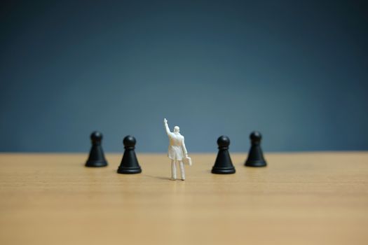 Miniature people strategic concept - businessman standing between losses or dropped pawn