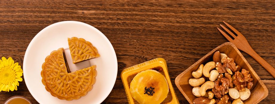 Moon cake for Mid-Autumn Festival, delicious beautiful fresh mooncake on a plate over dark wooden background table, top view, flat lay layout design concept.