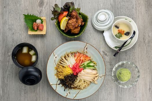Top view of japanese foods set, ramen with fried chicken karaage rice serve with egg stream, soup and ice scream over the wooden table, luxury japanese food concept