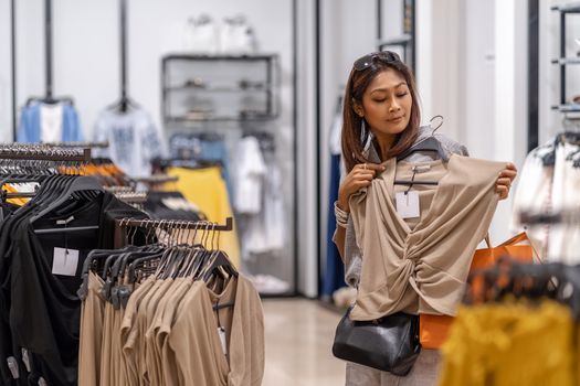 Happy Asian woman choosing clothes in shop store with happy action at department center