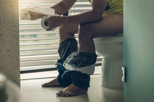 Man using the Tissue when sitting on toilet bowl