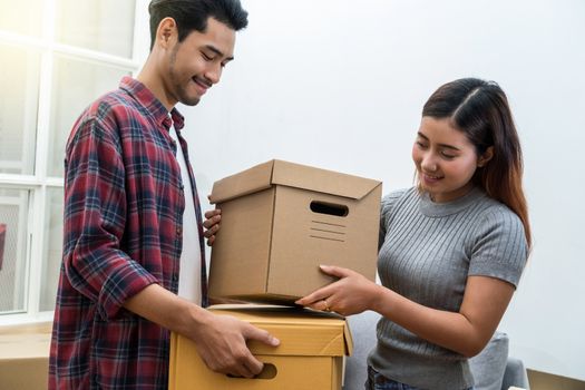 Asian young couple carrying big cardboard box for moving in new house, Moving and House Hunting concept