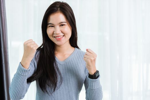 Asian portrait happy beautiful woman healthy smiling face long hair raise hand make success or winning yes gesture, studio shot looking to camera at home and have a copy space for your text