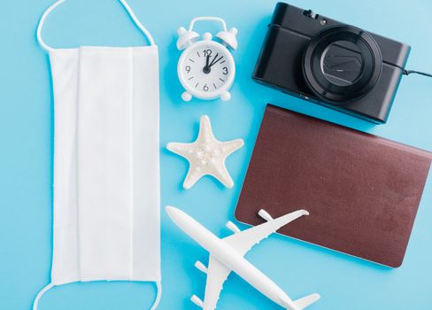 World Tourism Day, Top view of minimal model plane, airplane, starfish, compass, smartphone blank screen and face mask isolated on blue background, accessory flight holiday under coronavirus concept