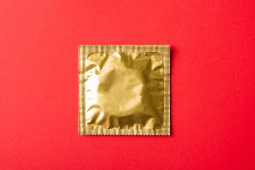 World sexual health or Aids day, Top view flat lay condom in wrapper pack, studio shot isolated on a red background, Safe sex and reproductive health concept