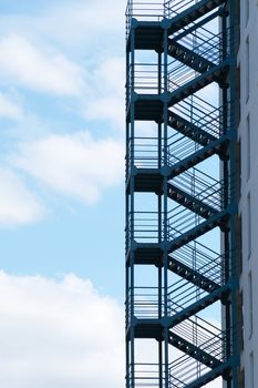 metal fire escape on the wall of a residential building against the background of the sky