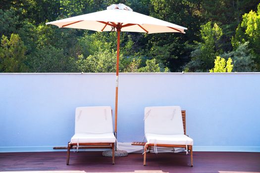 two sun loungers under an umbrella on the outdoor patio.